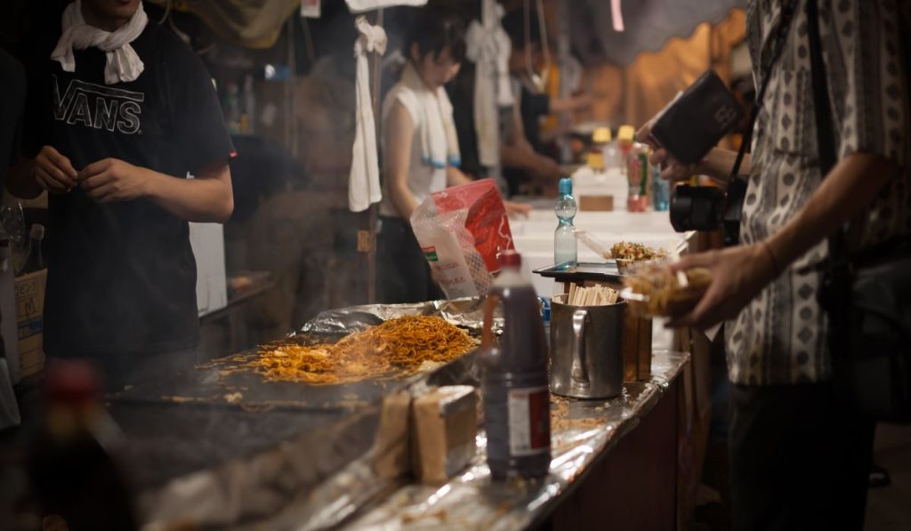 Street food cooking in Old Delhi Chandni Chowk with vendors preparing noodles and snacks