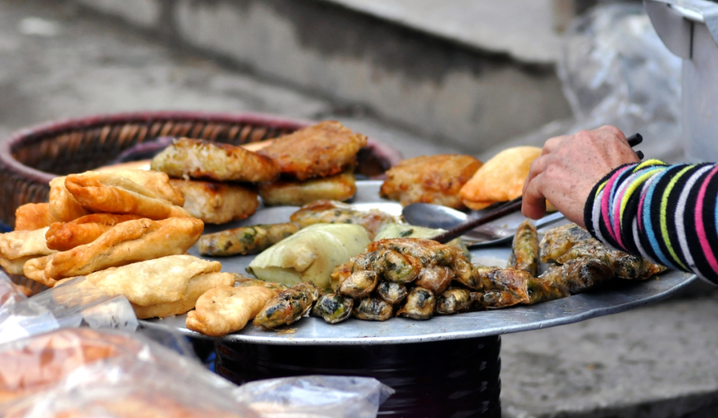 Famous fried street food snacks in Old Delhi market with local vendor serving food