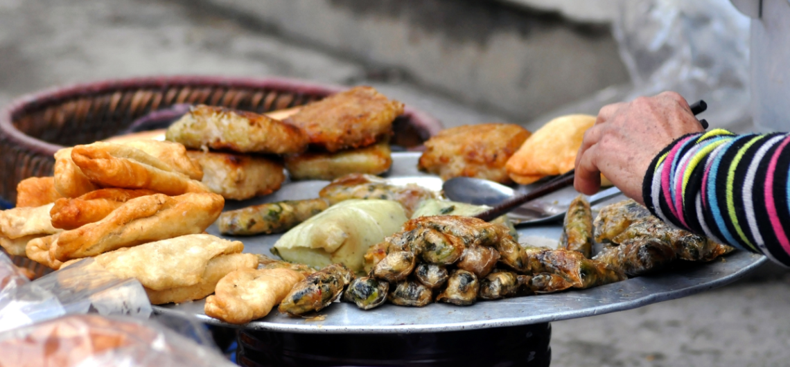 Famous fried street food snacks in Old Delhi market with local vendor serving food