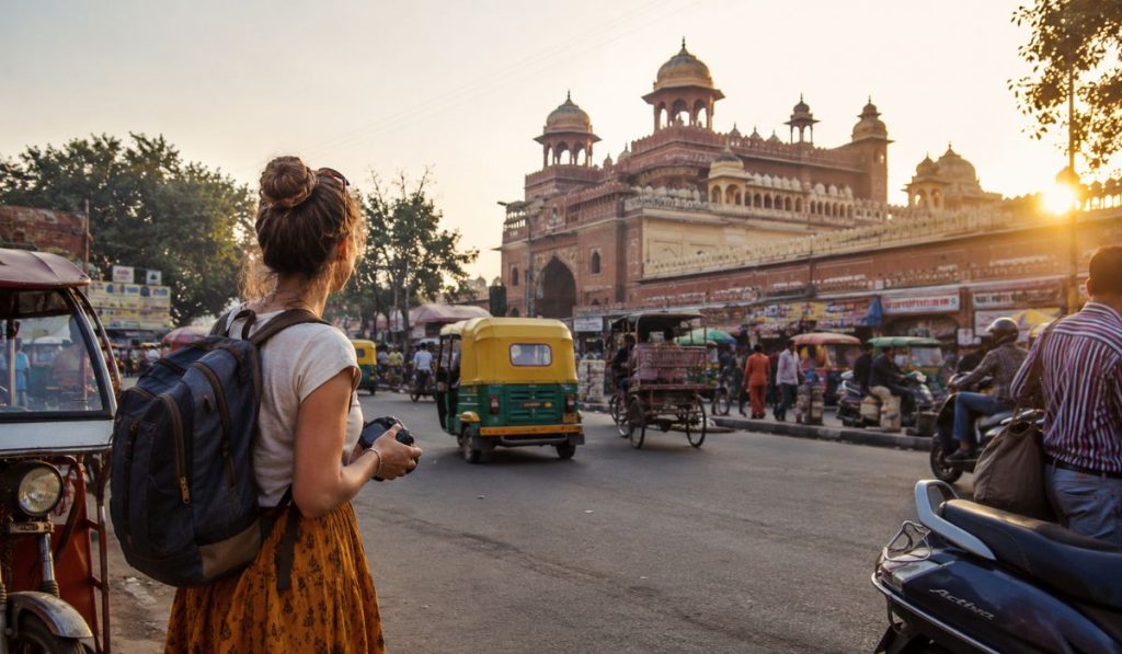 First-time foreign traveler exploring a busy street in India with tuk tuks and local traffic during sunset