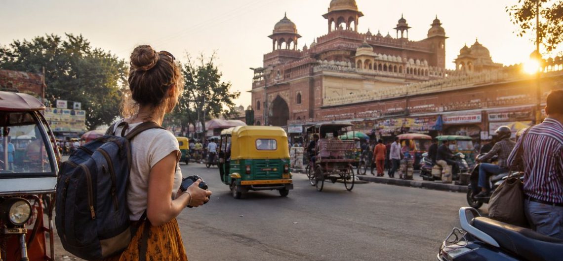 First-time foreign traveler exploring a busy street in India with tuk tuks and local traffic during sunset
